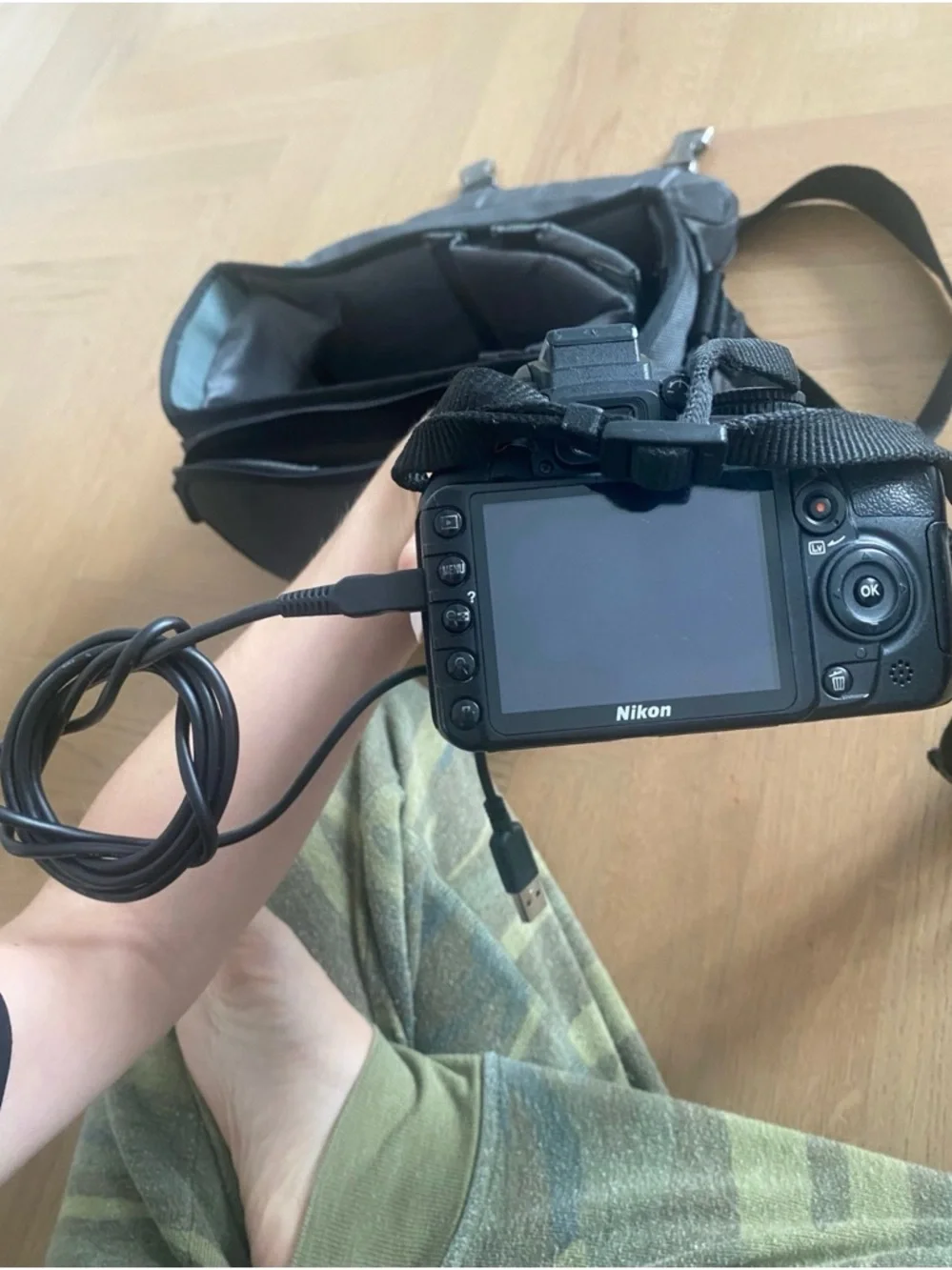 Nikon 3100 black DSLR with zoom lens and attached USB cable